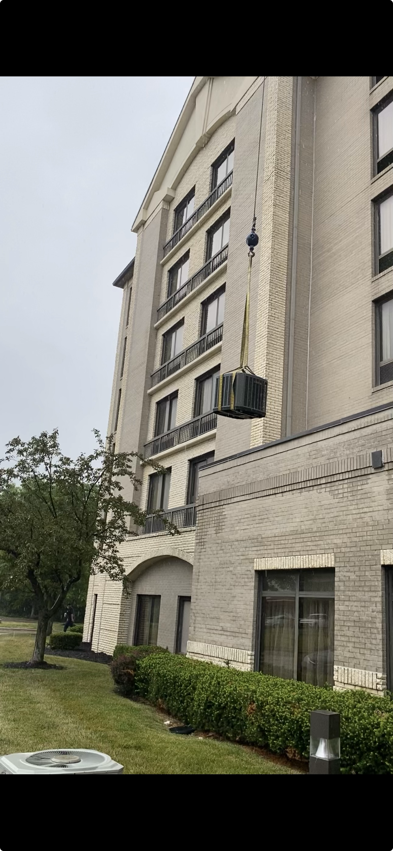 Crane lifting HVAC equipment onto a hotel building.