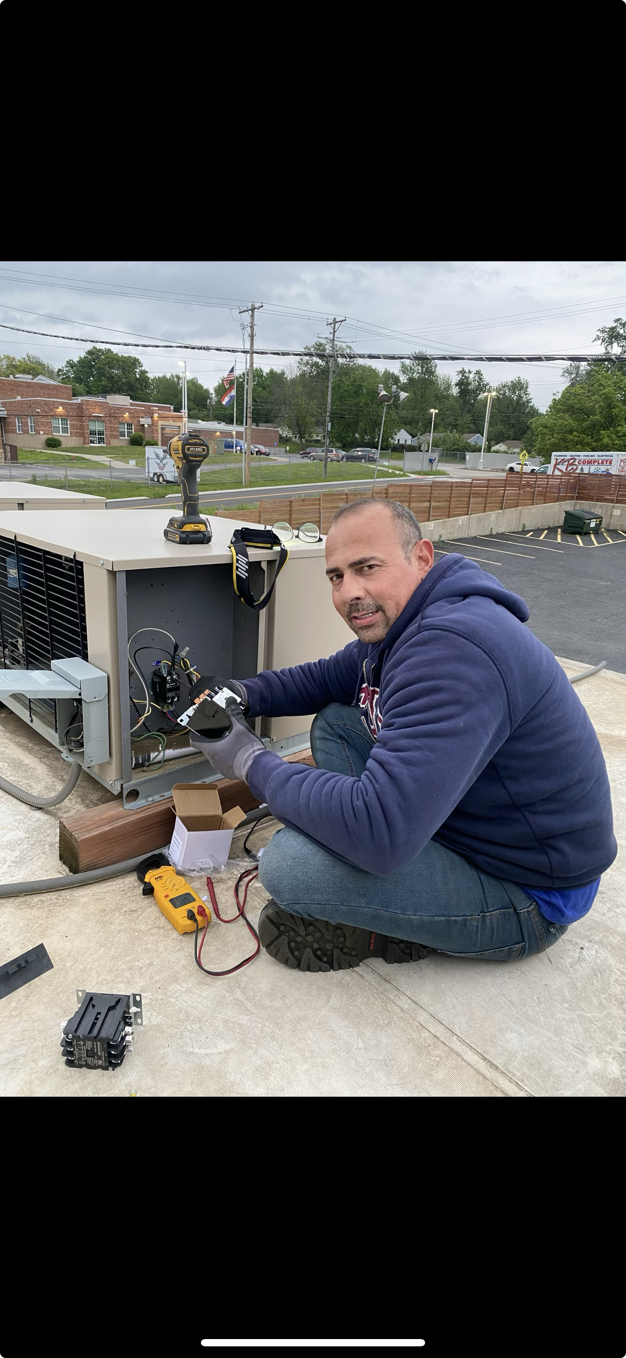 Albater technician diagnosing a rooftop HVAC unit with a multimeter.